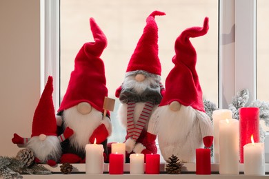 Cute Christmas gnomes and other festive decorations on windowsill in room