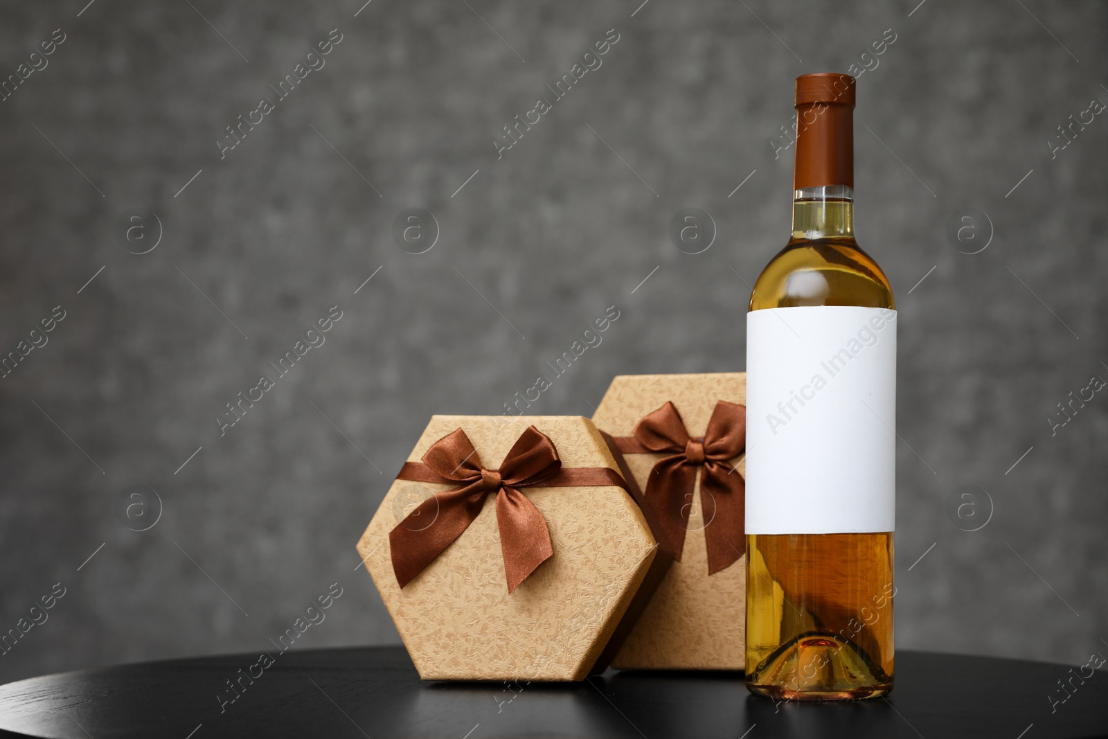 Photo of Gift boxes and bottle of wine on table. Space for design