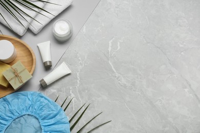 Photo of Flat lay composition with shower cap and toiletries on grey marble background. Space for text