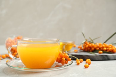 Photo of Delicious sea buckthorn tea and fresh berries on light grey table. Space for text
