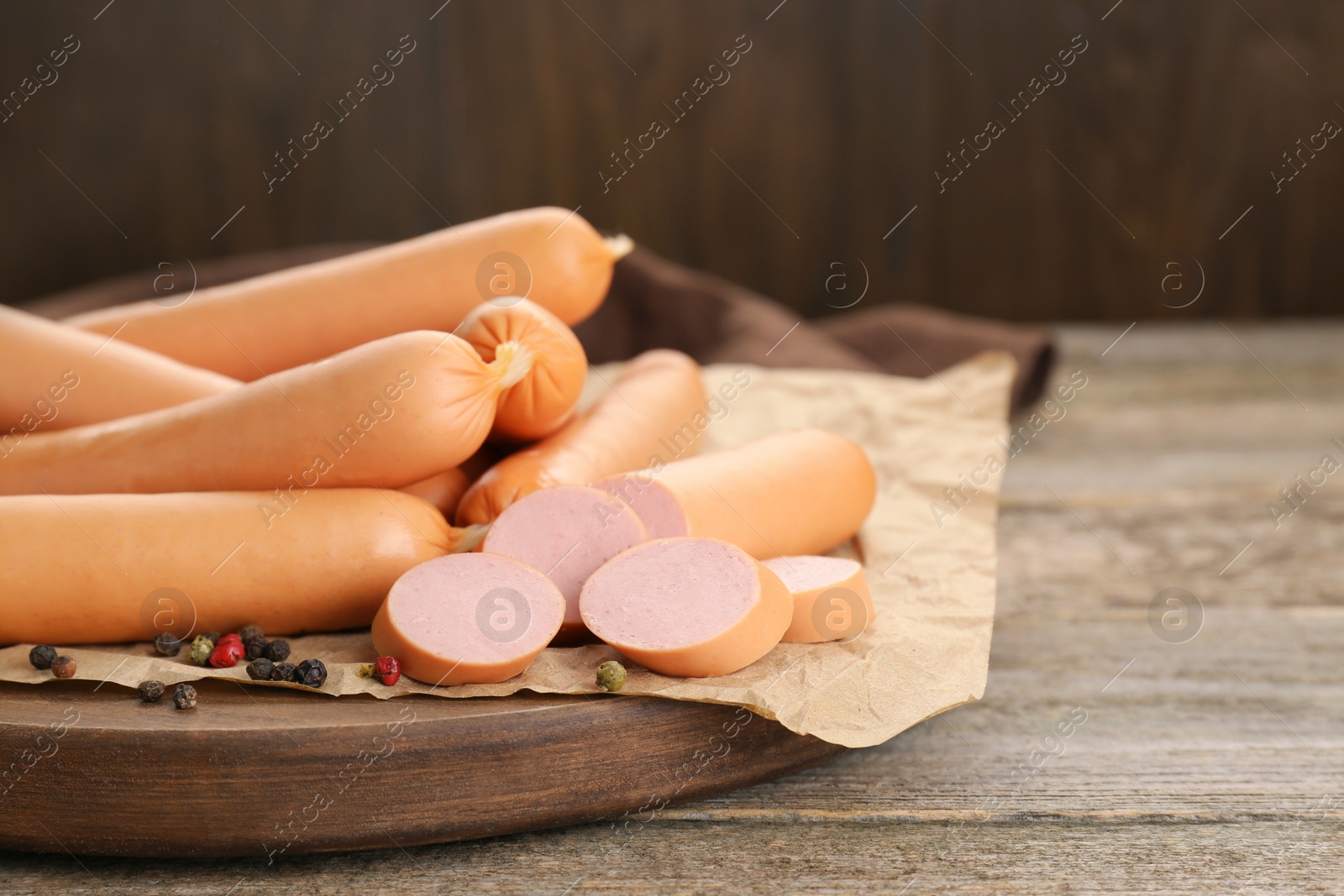 Photo of Tasty sausages and peppercorns on wooden table, closeup with space for text. Meat product