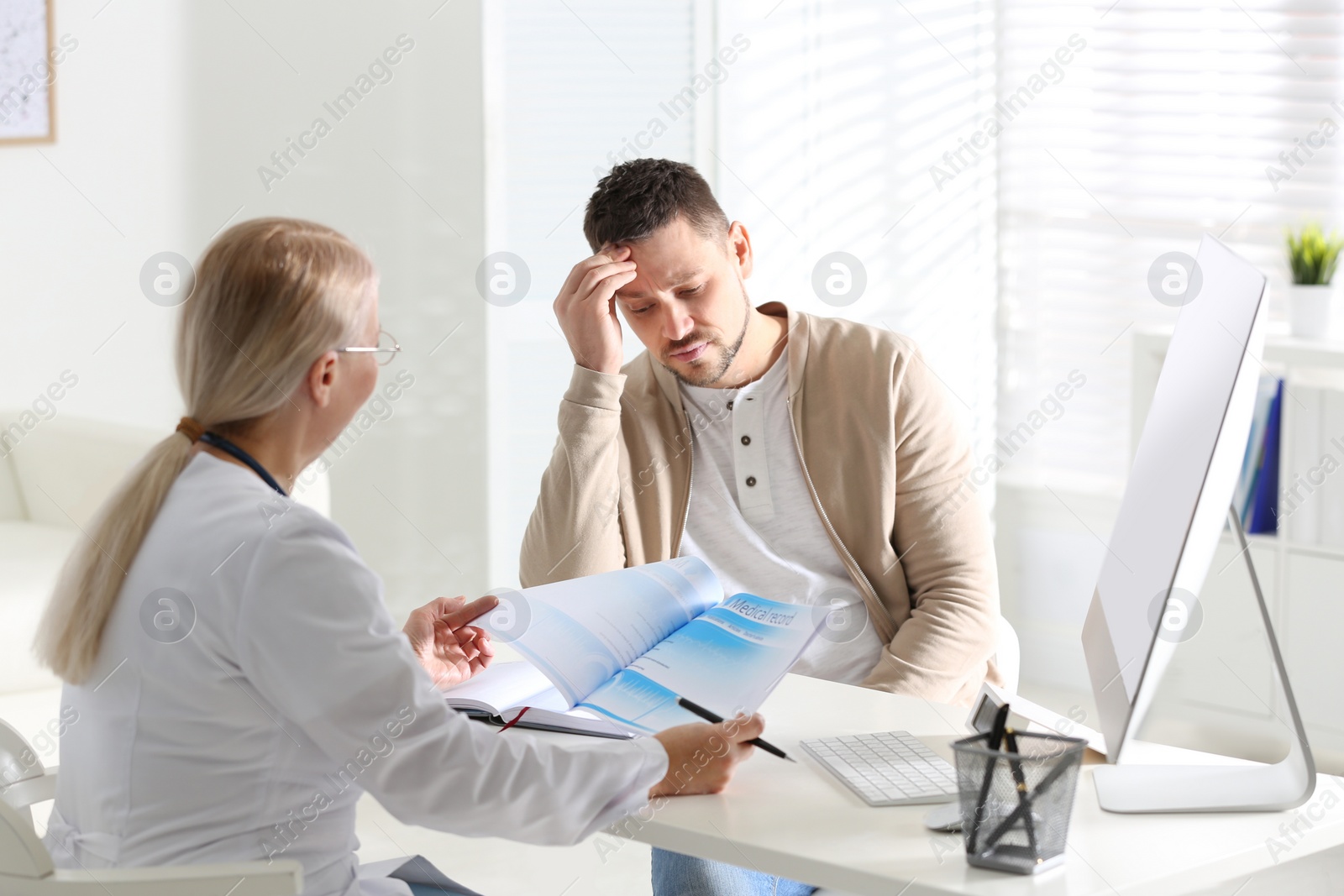 Photo of Doctor consulting patient at desk in clinic