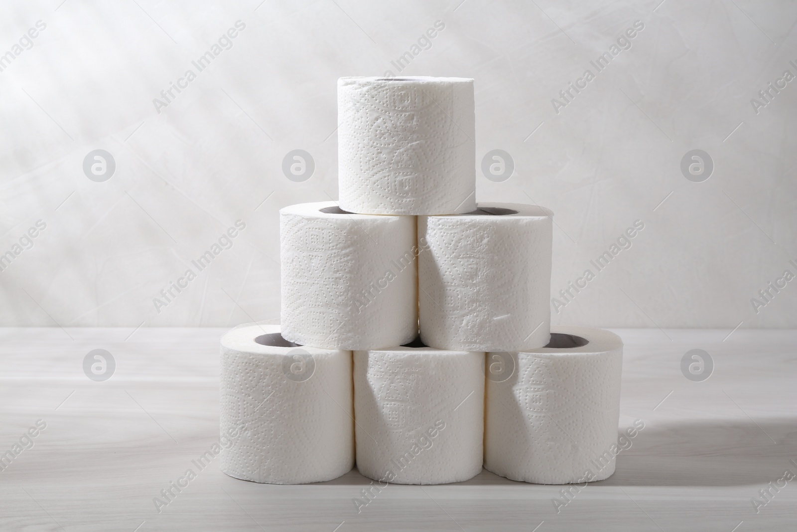 Photo of Pyramid of toilet paper rolls on white wooden table