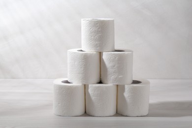 Photo of Pyramid of toilet paper rolls on white wooden table