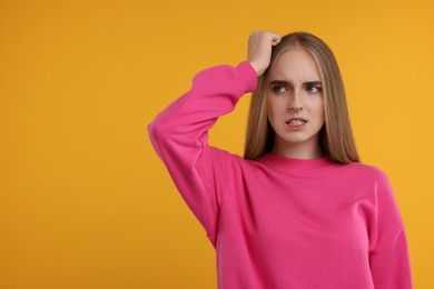 Photo of Portrait of embarrassed young woman on orange background, space for text
