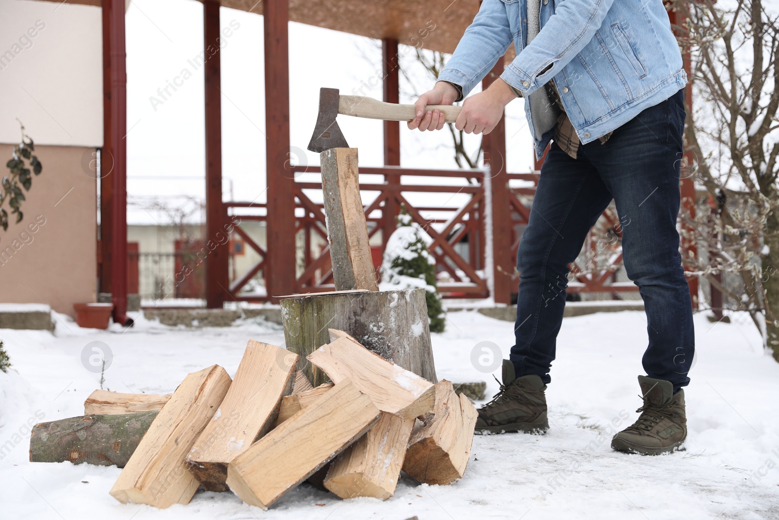 Photo of Man chopping wood with axe outdoors on winter day, closeup