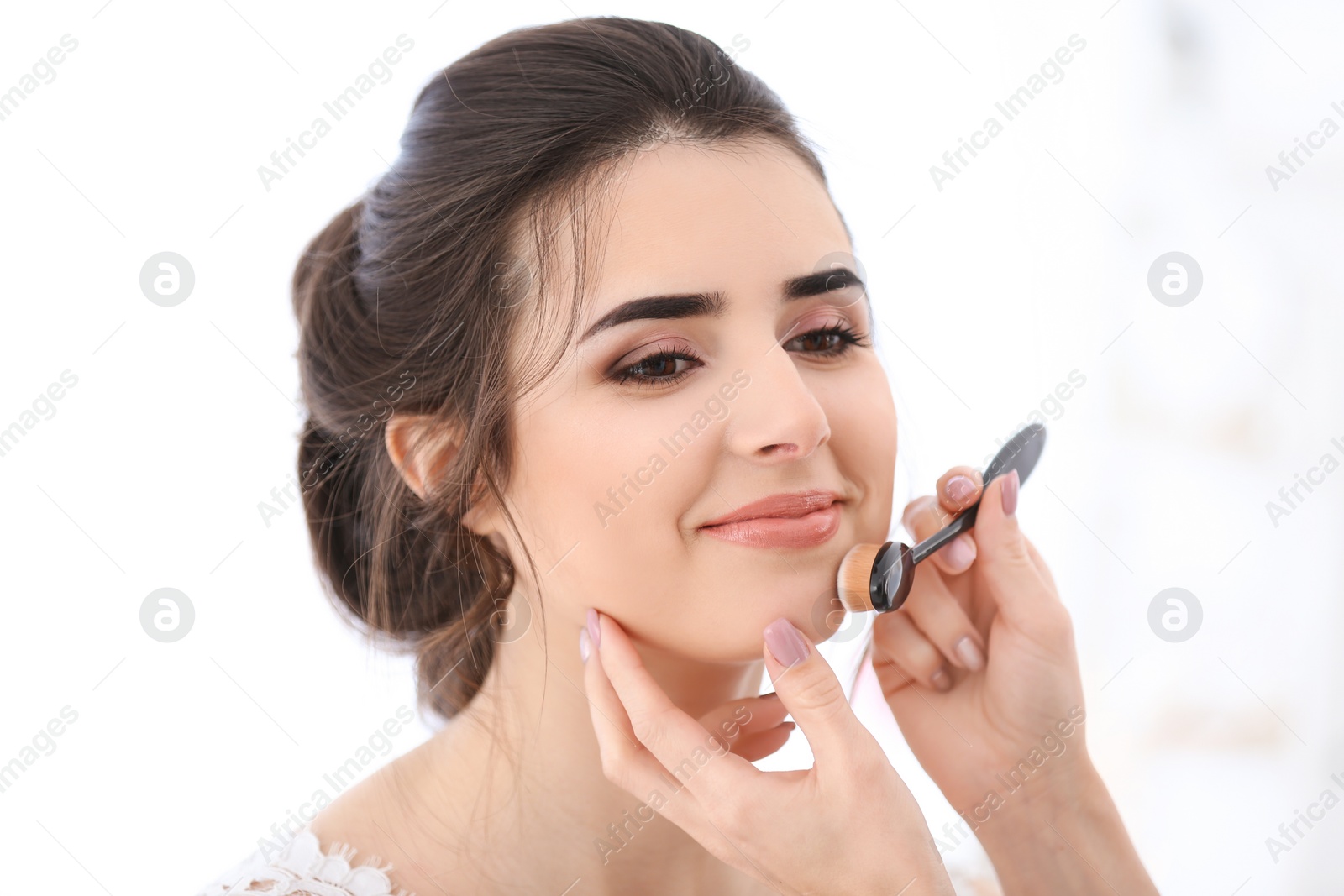 Photo of Professional makeup artist working with young woman in salon