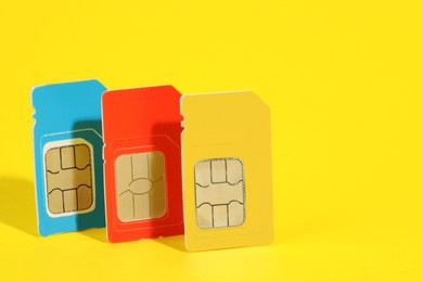 Photo of Different SIM cards on yellow background. Space for text