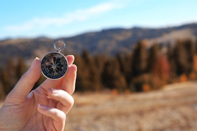 Photo of Traveler searching direction with compass in wilderness, closeup. Space for text