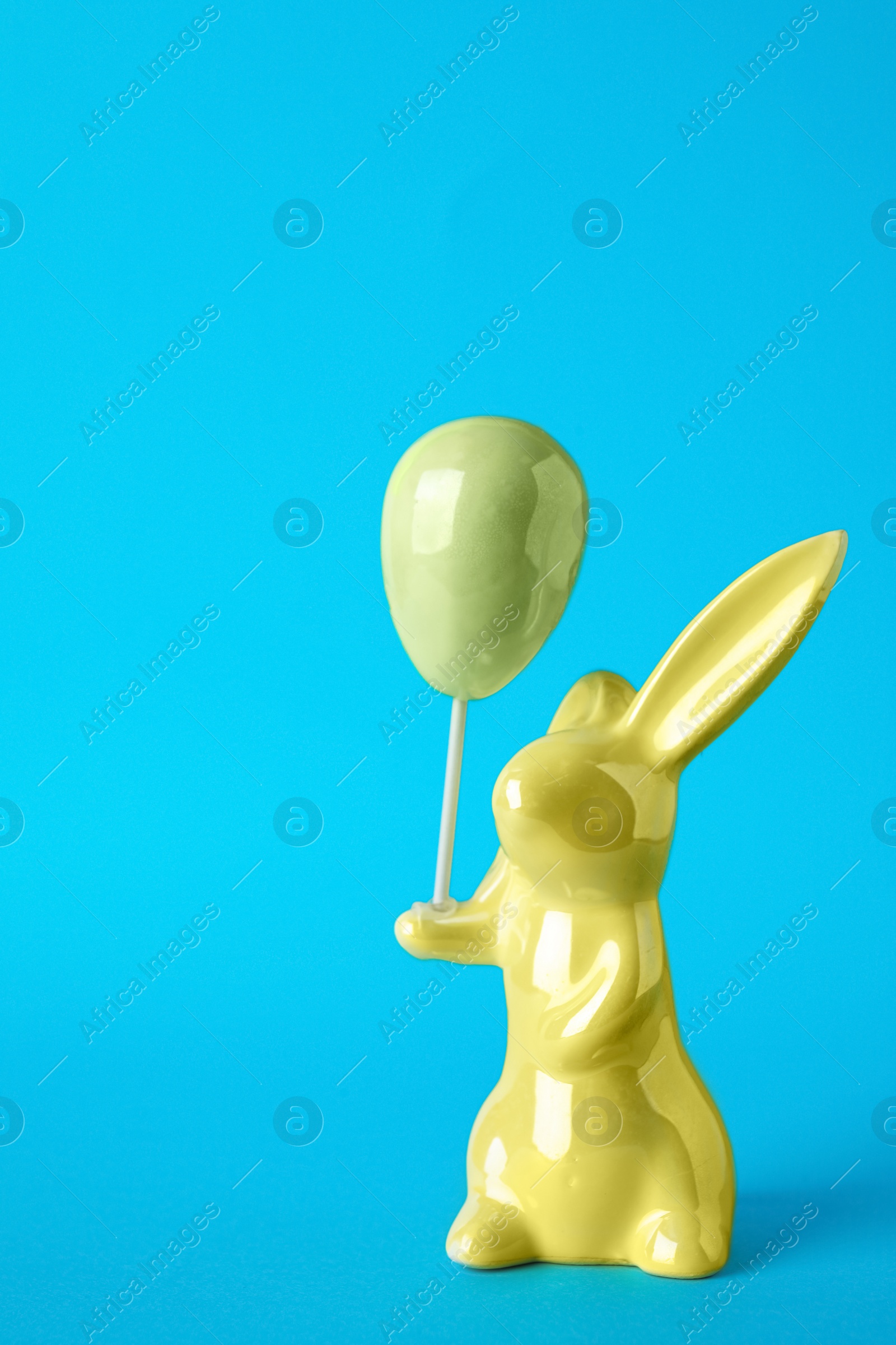 Photo of Bunny ceramic figure as Easter decor on blue background