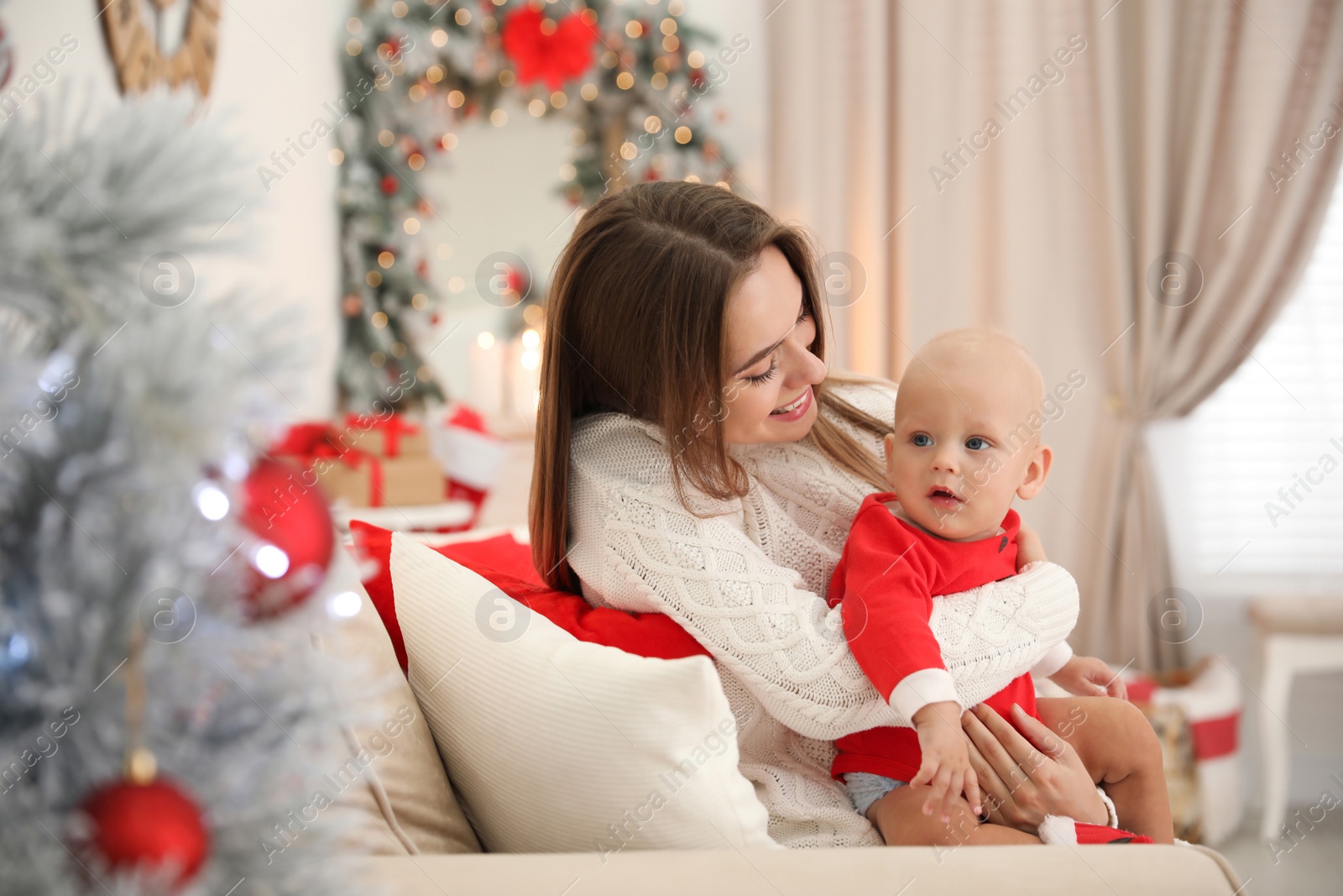 Photo of Happy mother with cute baby in room decorated for Christmas holiday