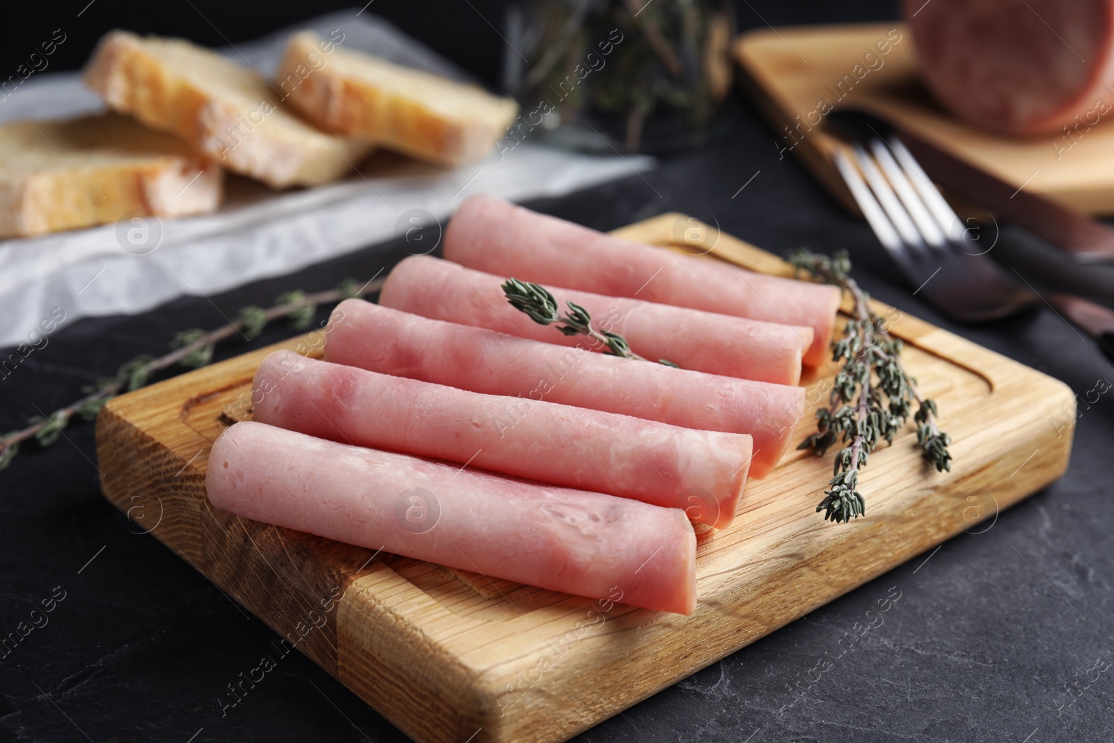 Photo of Slices of tasty ham on black table, closeup