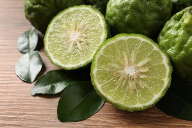 Fresh ripe bergamot fruits with green leaves on wooden table, closeup