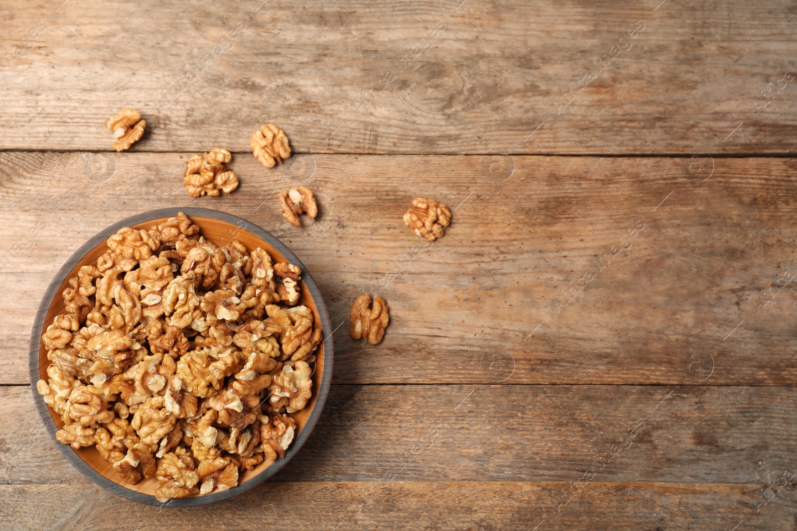 Photo of Plate with walnuts and space for text on wooden background, top view