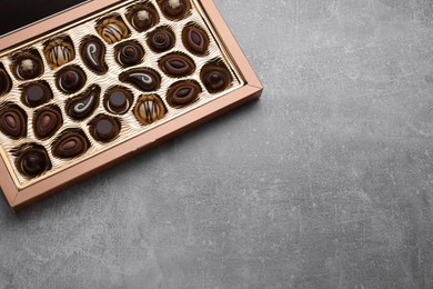 Photo of Box of delicious chocolate candies on light grey table