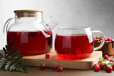 Photo of Tasty hot cranberry tea and fresh berries on wooden table