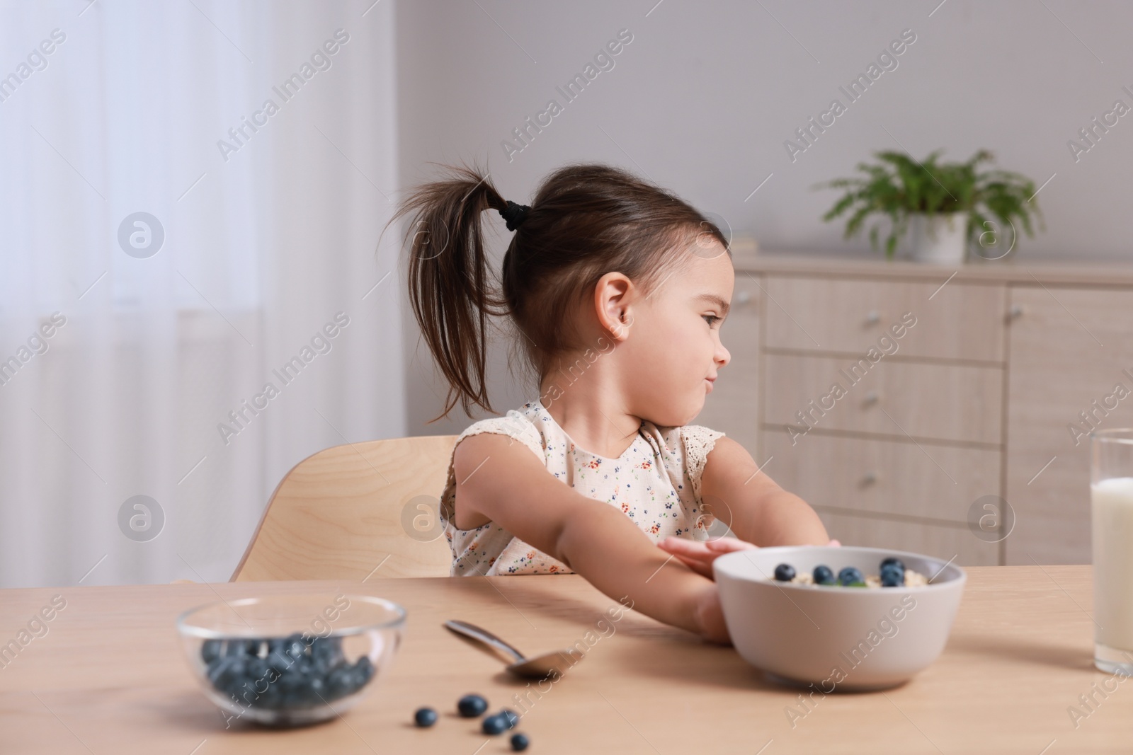 Photo of Cute little girl refusing to eat her breakfast at home