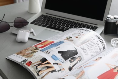 Photo of Workplace with fashion magazine on grey table, closeup