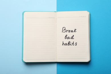 Open notebook with phrase Break Bad Habits on light blue background, top view