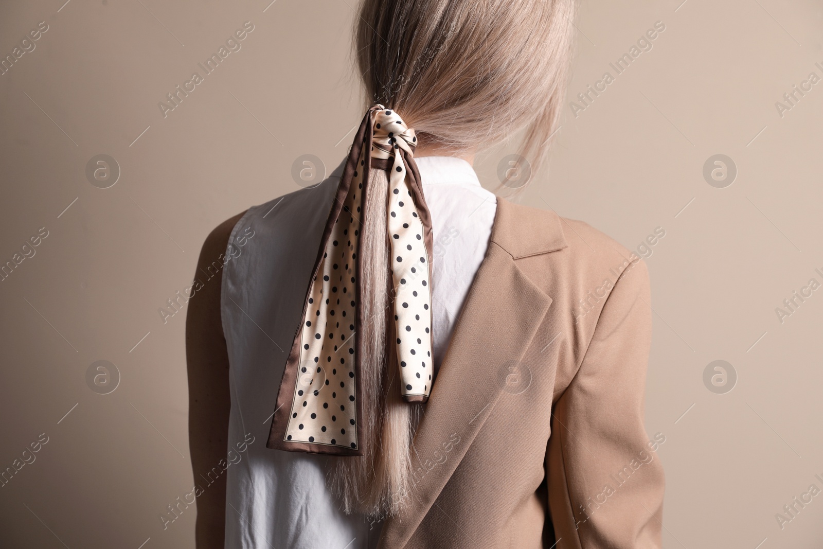 Photo of Young woman with stylish bandana on beige background, back view