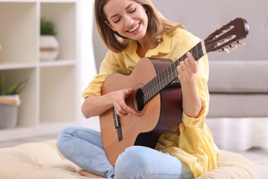 Photo of Young woman playing acoustic guitar at home