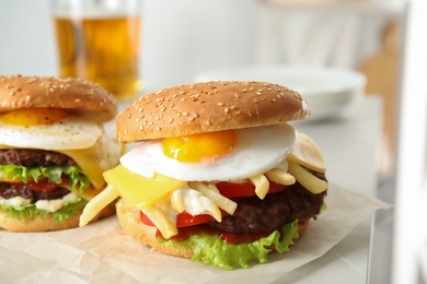 Tasty burgers with fried egg on parchment