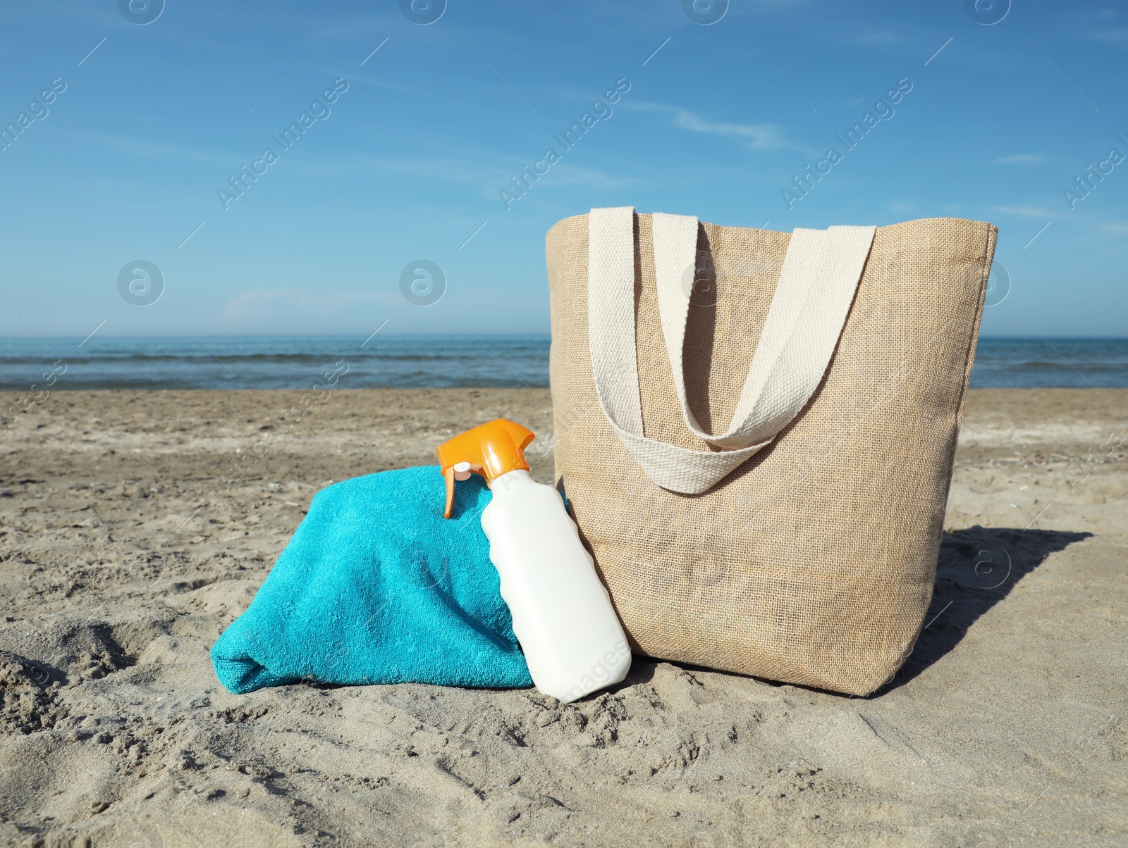 Photo of Bag, towel and sun protection product on sandy beach