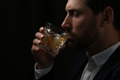 Photo of Man in suit drinking whiskey on black background