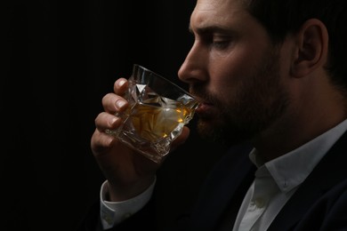 Man in suit drinking whiskey on black background