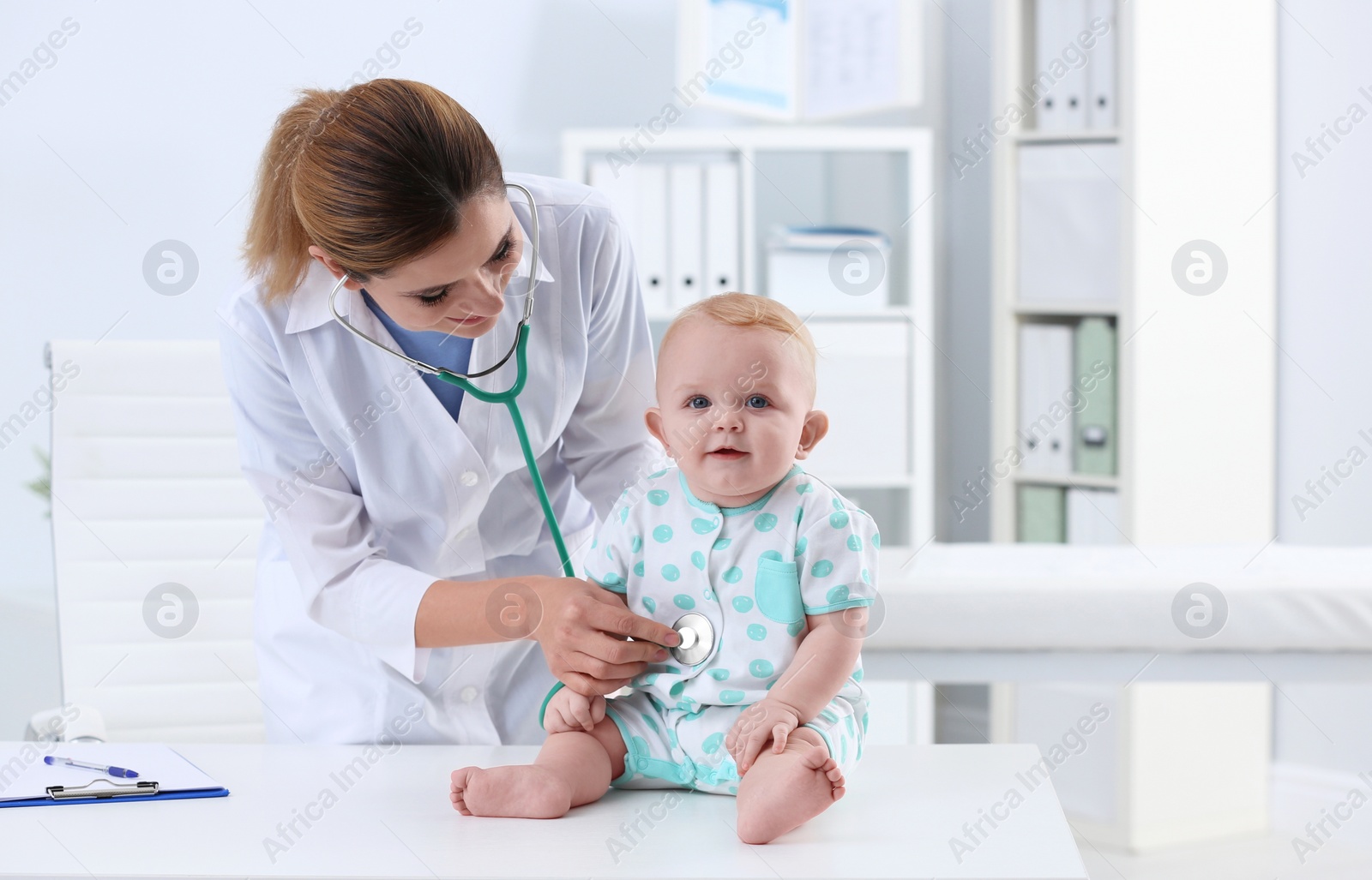 Photo of Children's doctor examining baby with stethoscope in hospital. Space for text