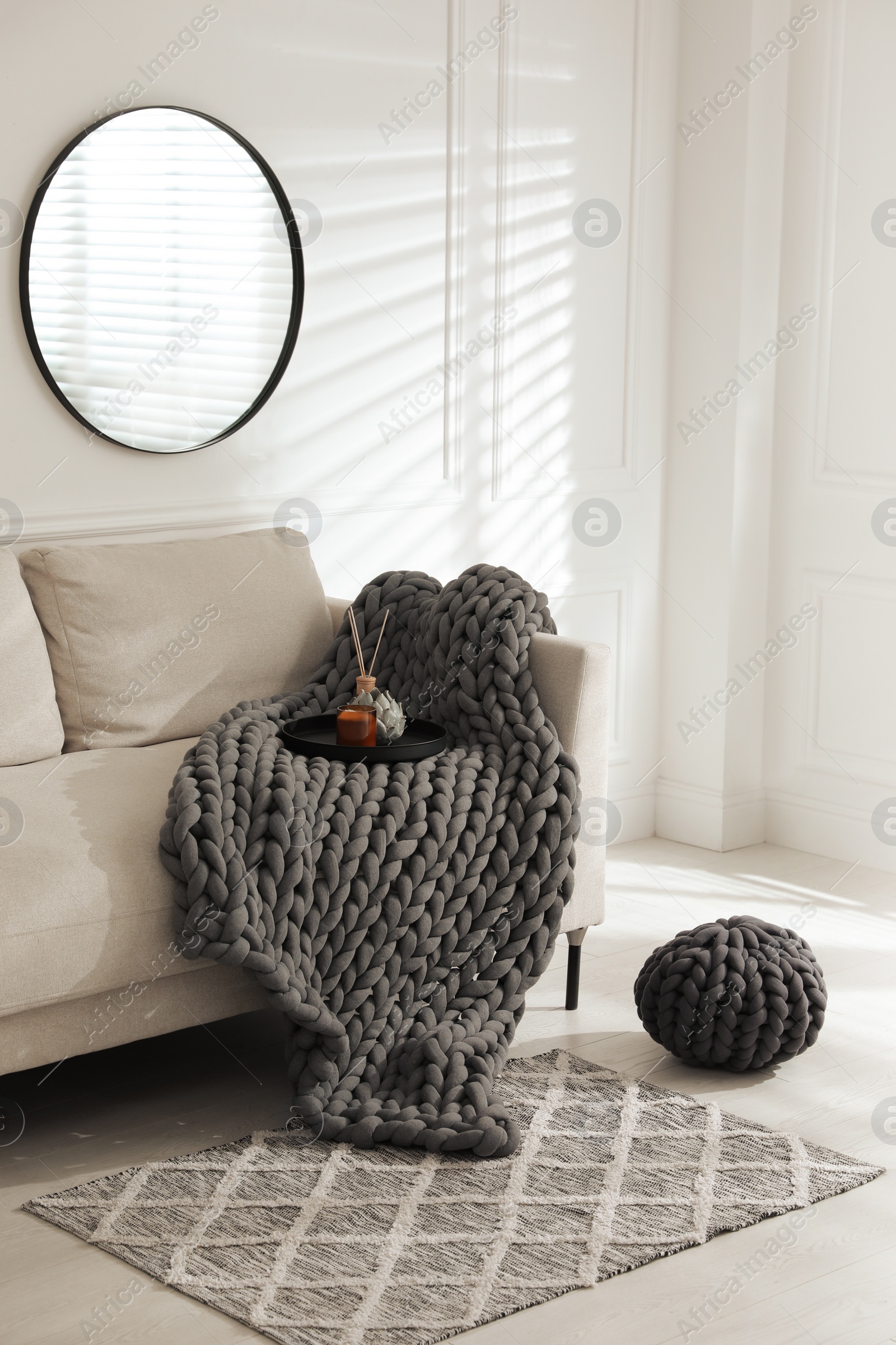 Photo of Soft chunky knit blanket on sofa in living room. Interior design