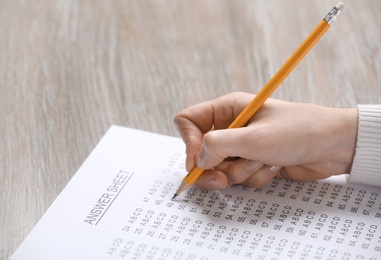 Photo of Student filling answer sheet at table, closeup