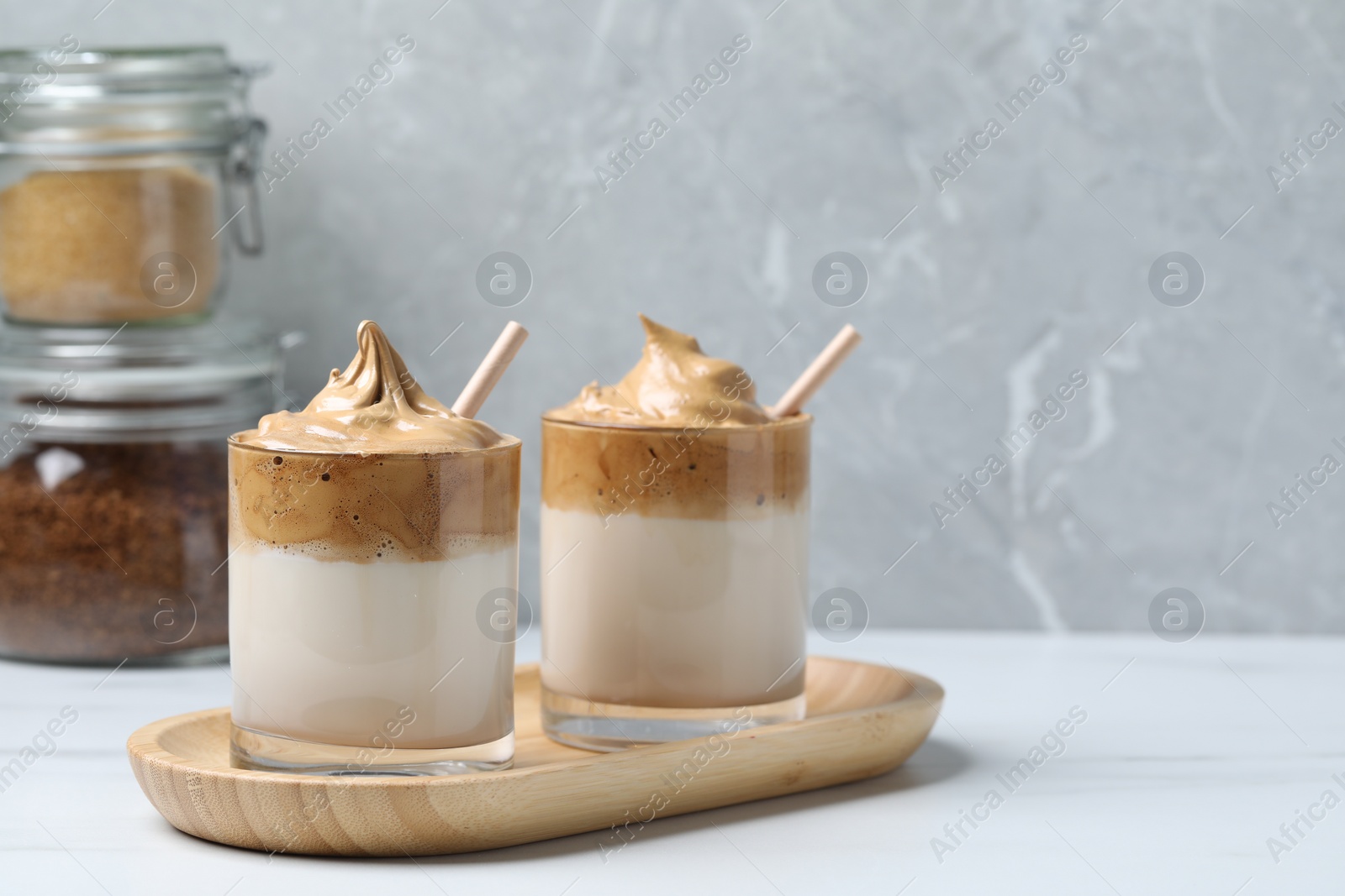 Photo of Glasses of delicious dalgona coffee on white table, space for text