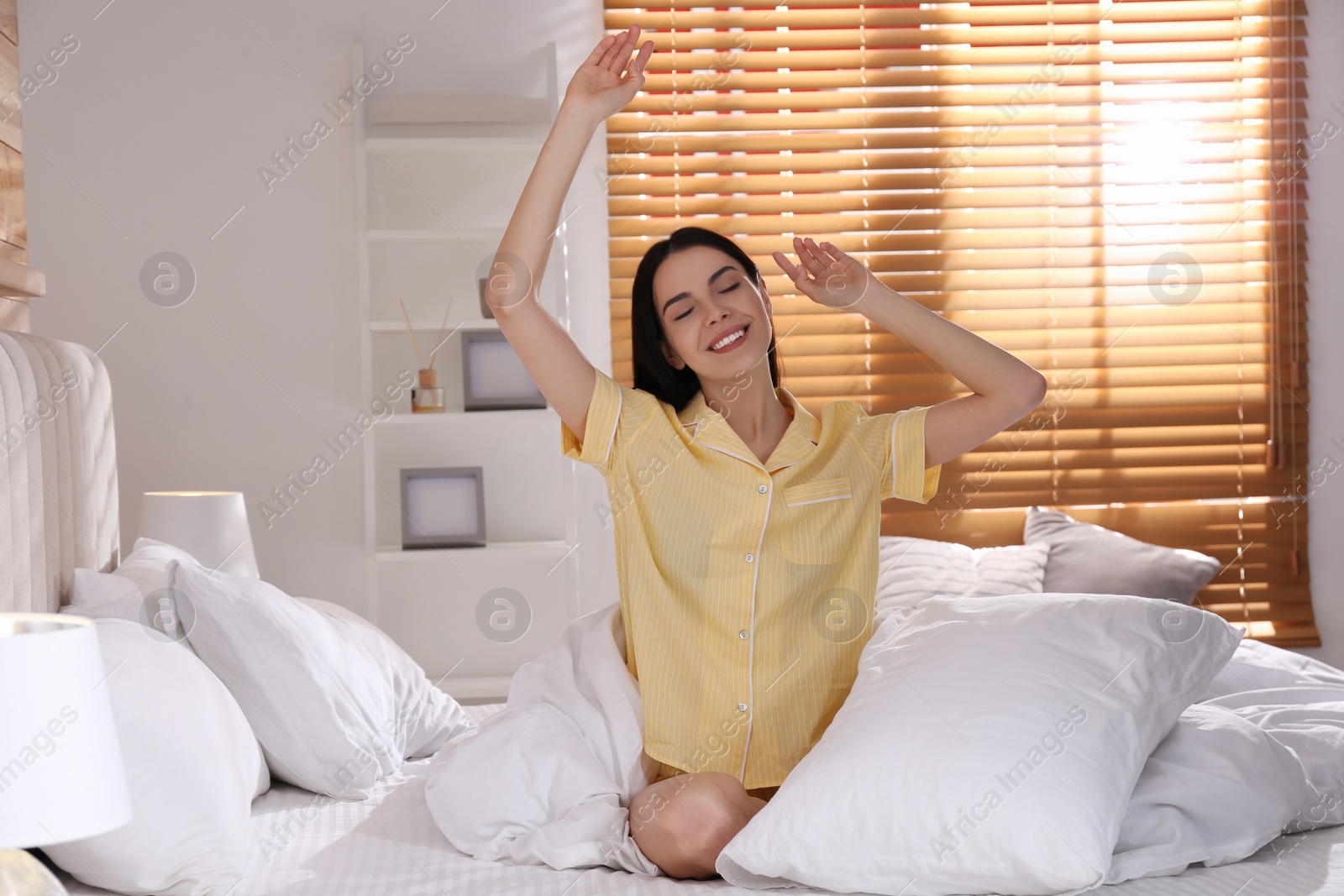 Photo of Woman sitting on comfortable bed with white linens