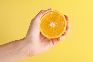 Photo of Woman squeezing juicy orange on beige background, closeup
