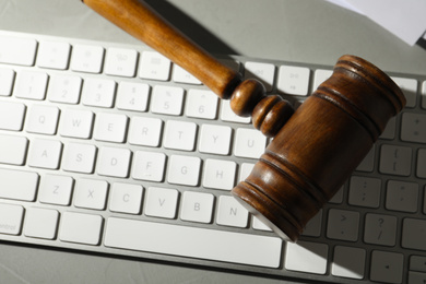 Photo of Gavel and computer keyboard on grey table, top view. Cyber crime