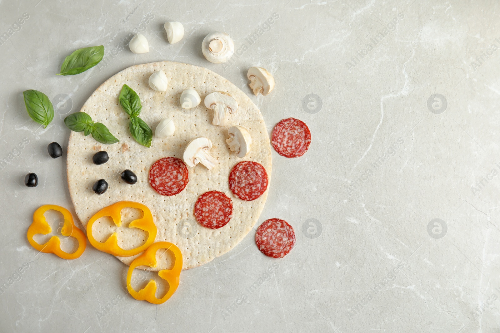 Photo of Flat lay composition with base and ingredients for pizza on marble table, space for text