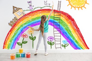 Image of Little girl drawing her dreams on wall, back view