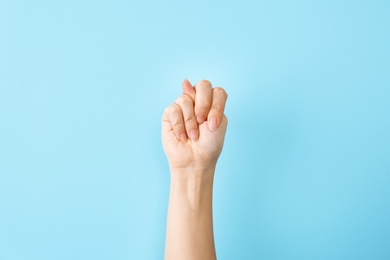 Woman showing N letter on color background, closeup. Sign language