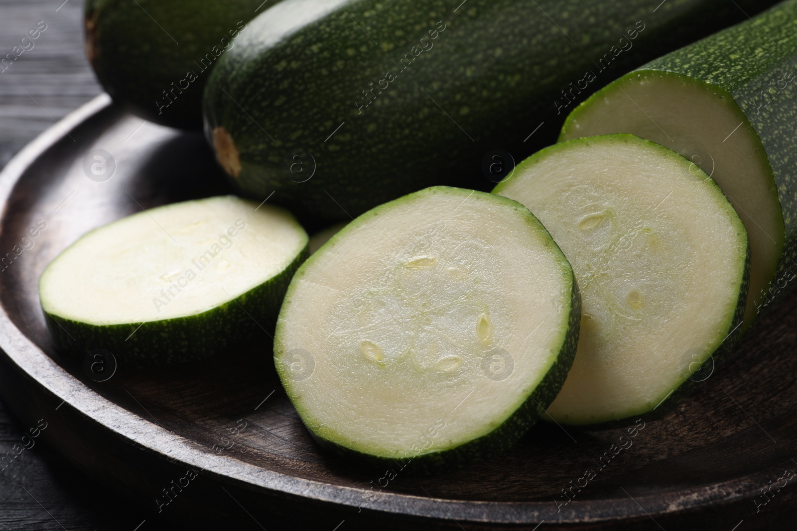 Photo of Whole and cut ripe zucchinis on plate, closeup