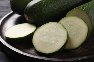 Whole and cut ripe zucchinis on plate, closeup