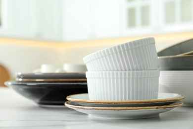 Photo of Set of ceramic tableware on white table in kitchen, closeup