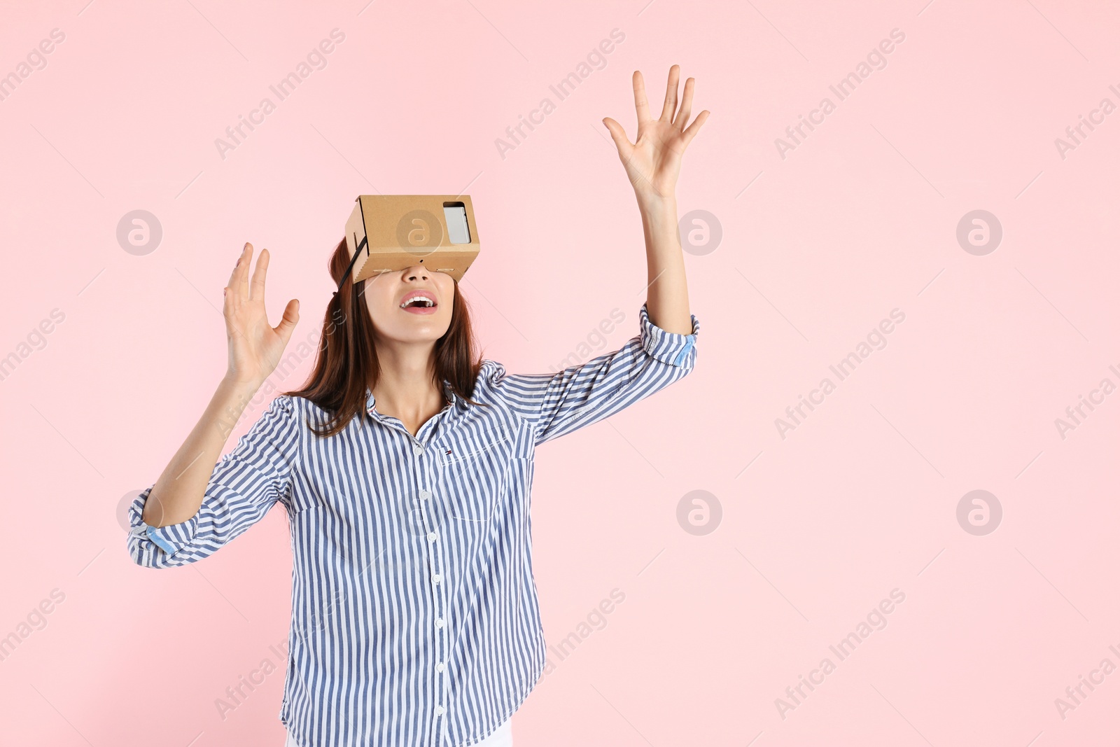 Photo of Young woman using cardboard virtual reality headset on color background. Space for text