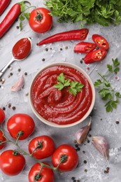 Flat lay composition with organic ketchup in bowl on grey textured table. Tomato sauce