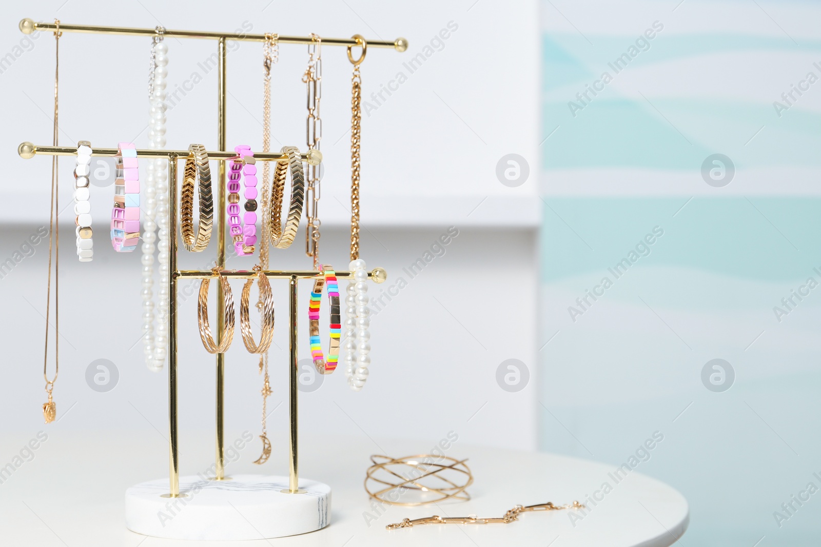 Photo of Holder with set of luxurious jewelry on white table in room. Space for text