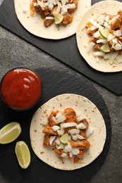 Photo of Delicious tacos with vegetables, meat and ketchup on grey textured table, flat lay