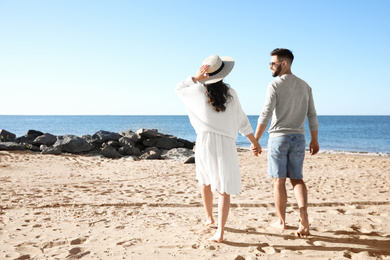 Photo of Happy young couple walking on beach near sea. Honeymoon trip