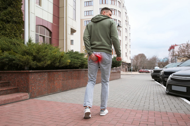 Man suffering from hemorrhoid outdoors, back view