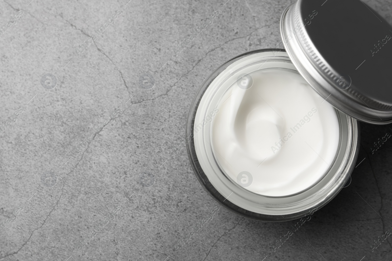 Photo of Jar of face cream on grey table, top view. Space for text