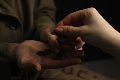 Woman giving coins to homeless, closeup. Charity and donation